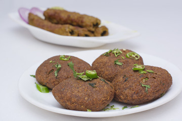 Close-up of cutlets with seekh kababs in background on table