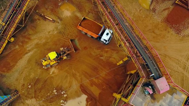 Excavator loader loading sand into dumper truck. Aerial view. Excavator loader working on sandpit. Backhoe excavator loading sand in dumper truck. Wheel loader loading sand in tipper truck. Sand work