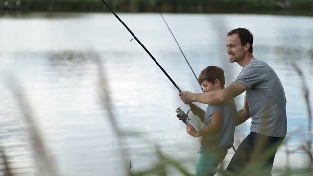 Excited father and son pulling fish out from lake