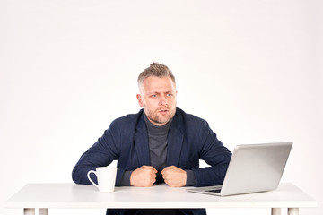 Portrait of middle-aged businessman sitting at office desk with laptop on it