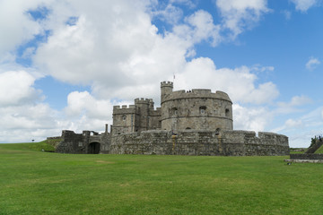 A castle in Cornwall at summertime with a blue sky with white clouds