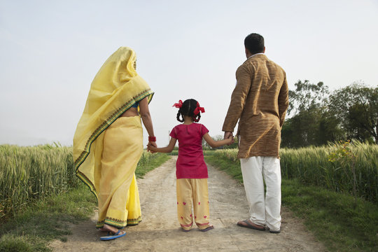 Back view of family walking together on a rural road 