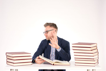 Portrait of middle-aged professor sitting at desk with book heaps on it