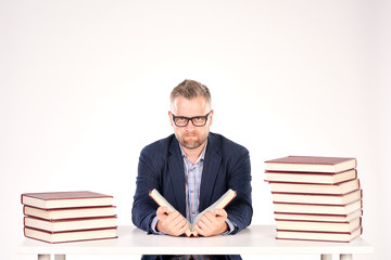 Portrait of middle-aged professor sitting at desk with book heaps on it