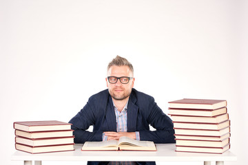 Portrait of middle-aged professor sitting at desk with book heaps on it