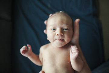 Overhead portrait of newborn baby boy held by father in hospital