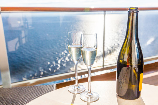 Champagne bottle and flutes glasses on luxury cruise travel for honeymoon holidays. Boat at sea on vacation sunset with celebration drinks.
