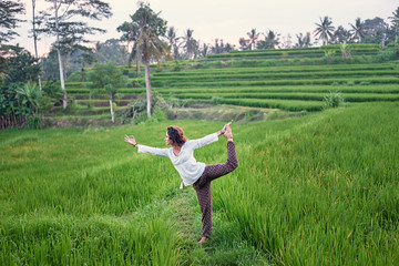Fototapeta na wymiar Young woman in asana pose standing on green grass. Concept of yoga and meditation.