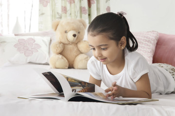Cute girl reading book in bed