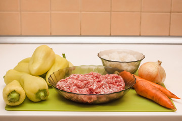 Homemade stuffed peppers with minced meat, carrots, onions, rice in kitchen. Cooking process. Stage of preparation of products