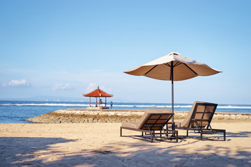 Vacation concept. Two sunloungers and umbrella on sand sea beach.