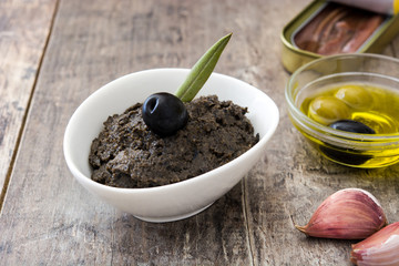 Black olive tapenade with anchovies, garlic and olive oil on wooden table
