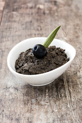 Black olive tapenade with anchovies, garlic and olive oil on wooden table
