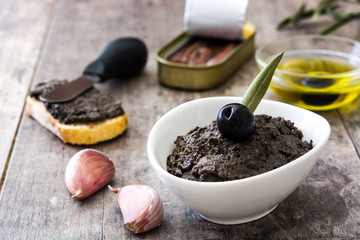 Black olive tapenade with anchovies, garlic and olive oil on wooden table
