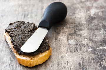 Black olive tapenade with anchovies, garlic and olive oil on wooden table
