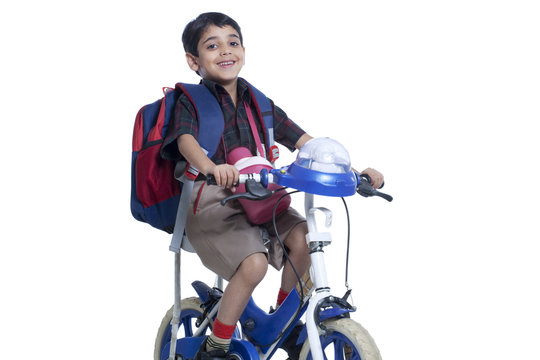 Happy school kid riding bicycle against white background 
