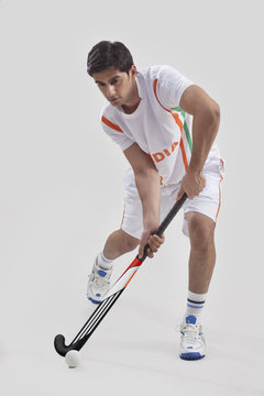 Young Man Playing Field Hockey Isolated Over Gray Background