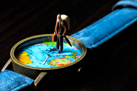 Aged man and world map travel watches. World travel photo banner. Senior traveler figurine.