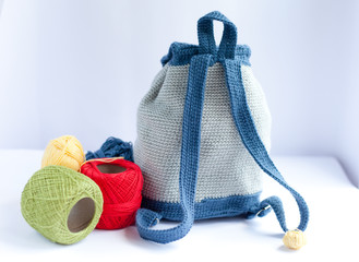 Handmade knitted backpack and colorful tangles of yarn