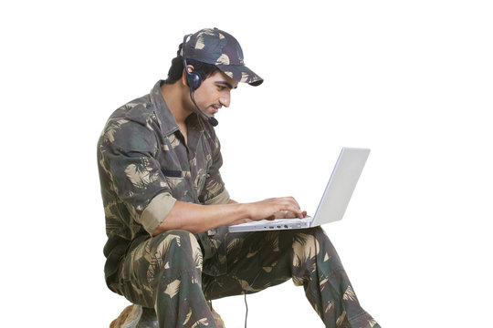 Young soldier using laptop over white background 