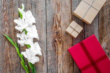 Colored gift boxes near flower on wooden background top view