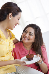 Daughter giving mother a cupcake