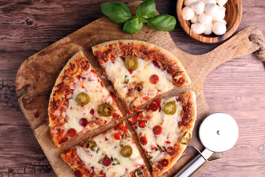 Hot pizza slice with melting cheese on a rustic wooden table. Italien food concept