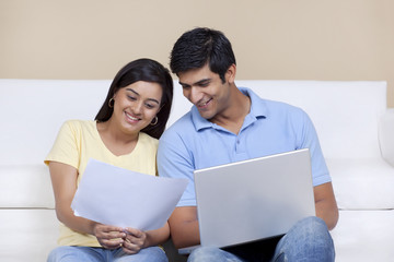 Obraz premium Woman holding paper while man using laptop 