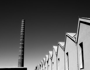 A former textile factory terrain with a chimney of brick, edited in black and white.
