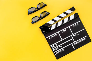 Fototapeta na wymiar Filmmaker accessories. Clapperboard and glasses on yellow background top view copyspace