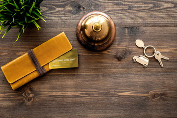 Book a hotel. Hotel service bell, bank card and room keys on dark wooden table background top view...
