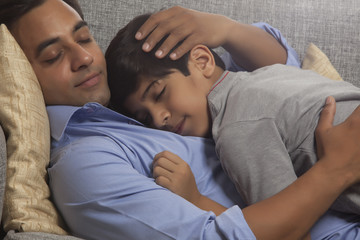Obraz na płótnie Canvas Father and son sleeping on sofa