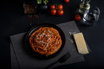 Spaghetti pasta with tomato sauce ,fresh tomato and cheese on dark background, selective focus