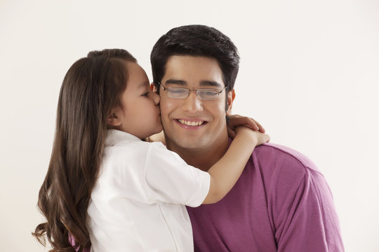 Cute girl kissing her father on white background 