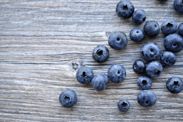A large bright juicy appetizing blueberry is scattered on a gray board