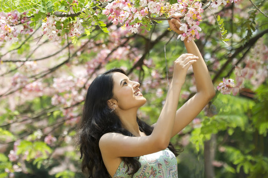 Young woman looking at flowers on a branch 