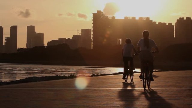 Silhouettes of people cycling at sunset; city of Shenzhen, Guangdong province, People's republic of China; 