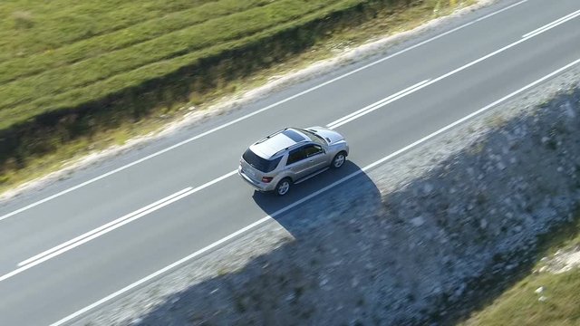 aerial view of a luxury car driving on country road