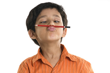 A boy with a pencil between his nose and lips 