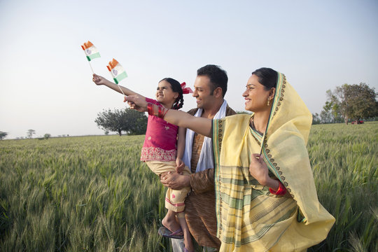 Rural family standing in the field holding Indian flag 