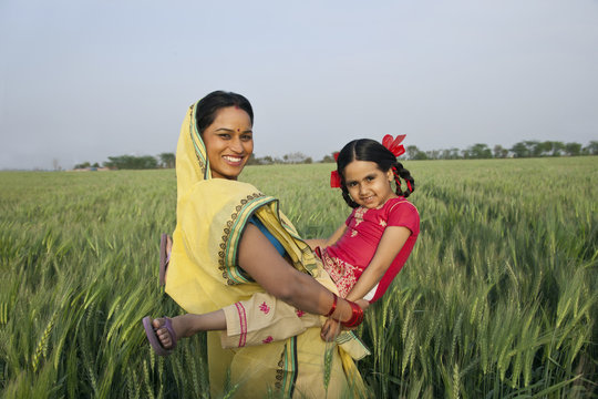 Portrait of an Indian mother playing with her daughter in the field 