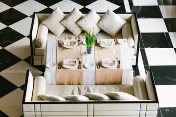 Stylish white dining table and sofas. Minimalist interior in monochrome. Black and white concept. Empty restaurant top view.
