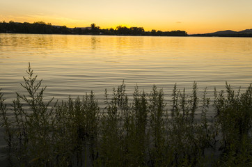 sunset, river view in summer. Colorful landscape summer sunset on the river bank. Sun rays and reflections on water