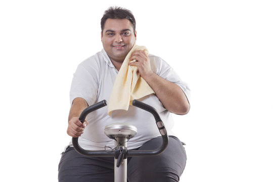 Portrait of a smiling obese man exercising over white background 