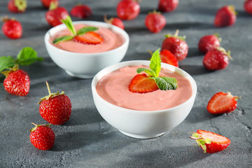 Delicious homemade yogurt with strawberry in bowls on dark background