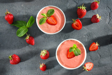 Delicious homemade yogurt with strawberry in bowls on dark background