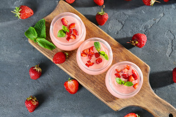 Delicious homemade yogurt with strawberry in jars on grey background