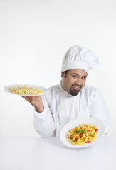 Portrait of chef holding plates with pasta