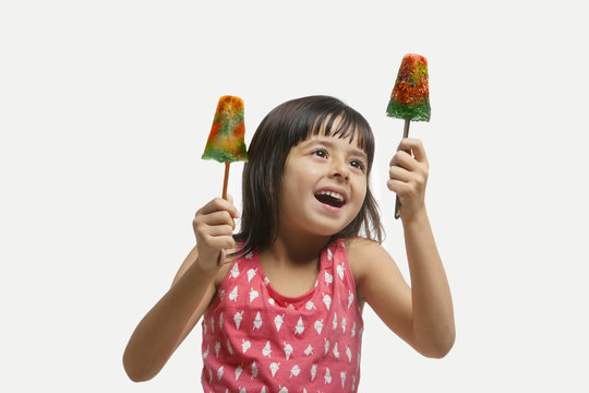 Little girl holding two ice lollies 