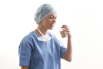 Happy young female surgeon drinking tea isolated over white background 